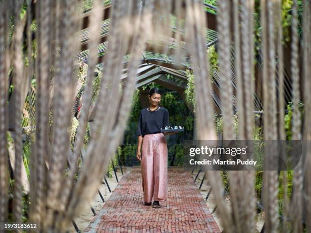 female spa therapist walking along ornate corridor leading to resort spa, holding a tray of natural oils - esclusivo foto e immagini stock