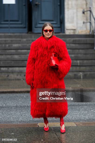 Nina Sandbech wears red faux fur coat, bag, red pants, heels, sunglasses, gloves outside Aeron during the Copenhagen Fashion Week AW24 on January 30,...