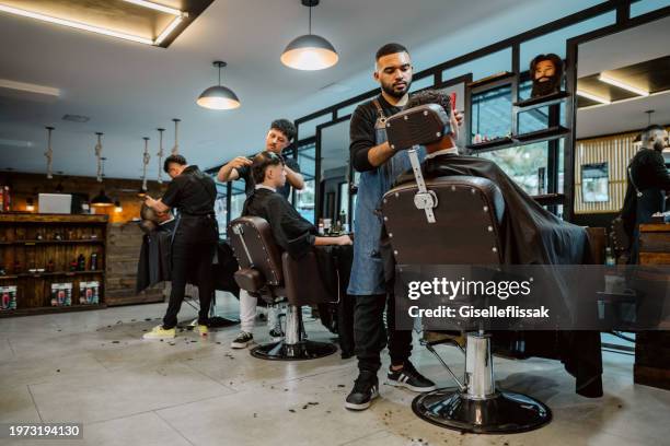 parrucchieri professionisti al servizio dei clienti in salone - negozio del barbiere foto e immagini stock