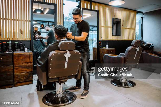 young professional hairdresser cutting hair of client in salon - male hairdresser stock pictures, royalty-free photos & images