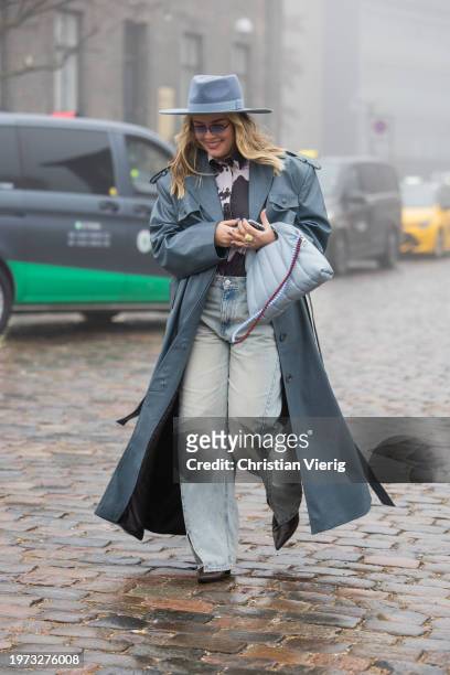 Guest wears hat, grey coat, blue bag outside Rolf Ekroth during the Copenhagen Fashion Week AW24 on January 30, 2024 in Copenhagen, Denmark.