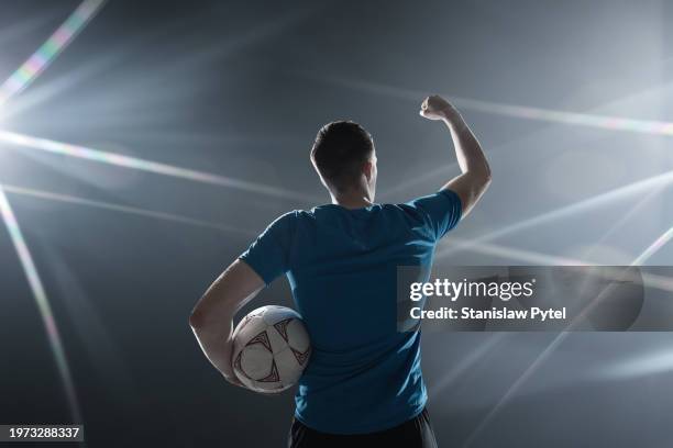 soccer player in blue outfit celebrating victory against dark background - football player stock pictures, royalty-free photos & images
