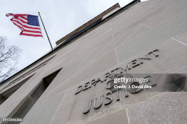 The US Flag flies above a sign marking the US Department of Justice headquarters building on January 20 in Washington, DC.