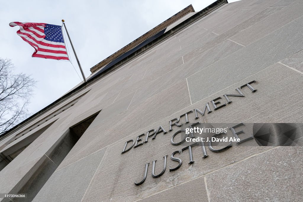 The US Flag flies above a sign marking the US Department of Justice ...