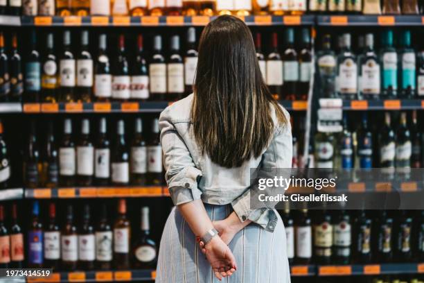 woman customer looking at a rack of wine in supermarket - alcohol drink stock pictures, royalty-free photos & images