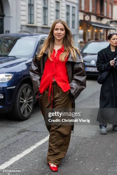 Trine Kjaer wears red blouse, brown wide leg pants, leather jacket outside Aeron during the Copenhagen Fashion Week AW24 on January 30, 2024 in...