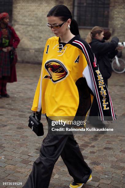 Guest wears black pants, a black and yellow shirt, and yellow sneakers outside Rolf Ekroth during the Copenhagen Fashion Week AW24 on January 30,...