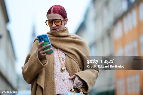 Guest wears sunglasses, a beige oversized long large fringed scarf, a matching long coat, pastel pink tweed jacket from Chanel, a blue bag from...