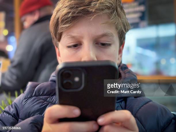 Year-old boy looks at a iPhone screen on January 26, 2024 in Bath, England. The amount of time children spend on screens each day rocketed during the...