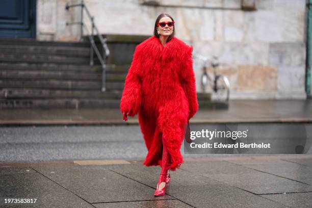 Nina Suess wears sunglasses, earrings, a bold red oversized fluffy faux fur long coat, stirrup leggings, pointed shiny shoes, outside Aeron, during...