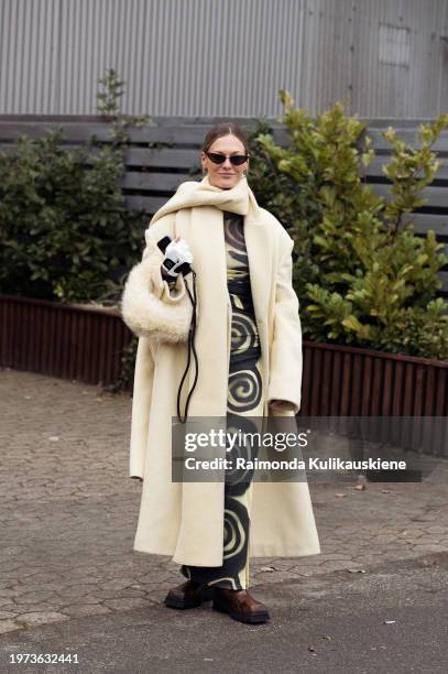 Guest wears a pale yellow and black long dress, pale yellow coat, matching fur bag, white and black Chanel gloves, and matching long scarf outside...