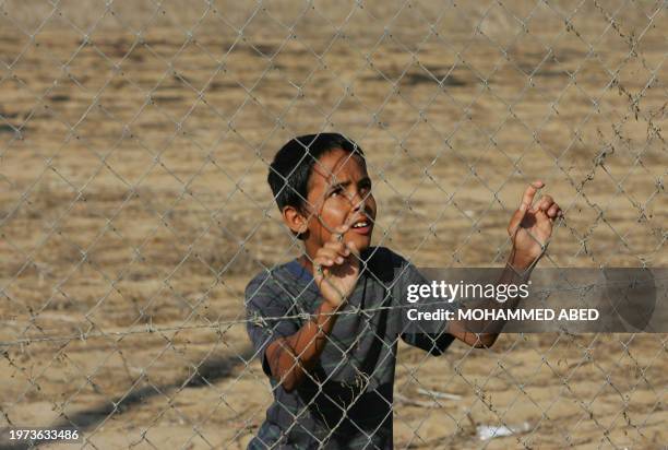 Palestinian boy standing behind a fence watches as the body of civilian Ibrahim al-Shami, who was killled during an Israeli incursion into the Gaza...