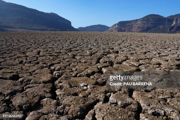This photograph taken on February 2, 2024 shows the dry soil next to the low water-level reservoir of Sau, in the province of Girona in Catalonia....
