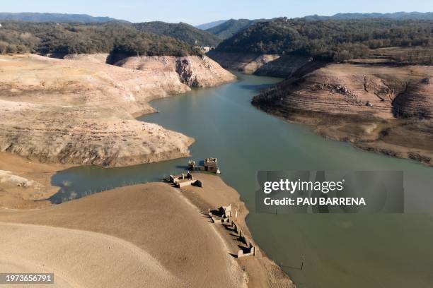 This aerial view taken on February 2, 2024 shows the dry soil and ruins on the bank of the low water-level reservoir of Sau in the province of Girona...