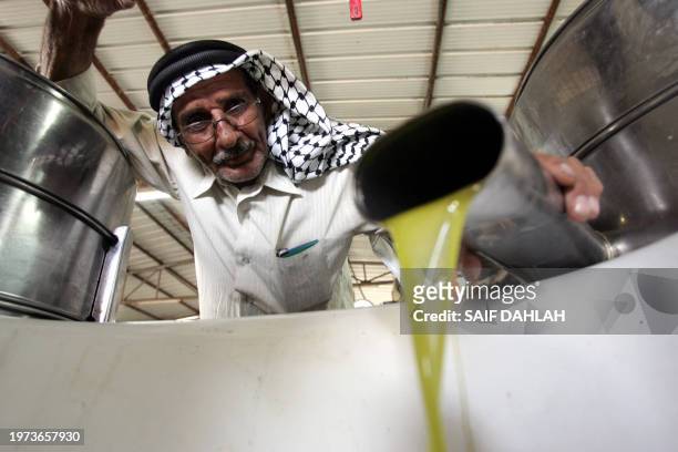 Palestinian man watches as he pours out his just pressed olive oil at the start of the olive harvesting season in the occupied West Bank village of...