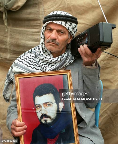 An elderly Palestinian man listens to the news about US President Bill Clinton's visit to Gaza, while he participates in a demonstration for the...