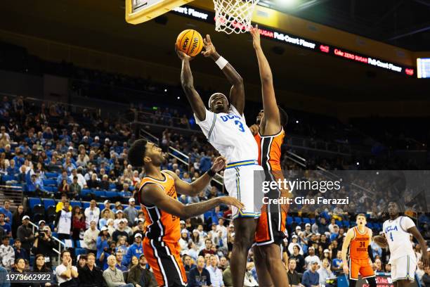 Bruins forward Adem Bona drives to the basket between Oregon State Beavers guard Justin Rochelin and Oregon State Beavers center KC Ibekwe in the...