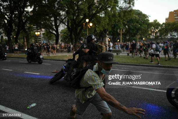 Demonstrator runs after kicking a police motorbike during a protest outside the Congress in Buenos Aires on February 2, 2024. Argentine lawmakers...