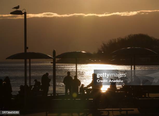 People enjoy the sunset at HTO Park's urban beach as daily life continues in Toronto, Ontario on February 2, 2024.