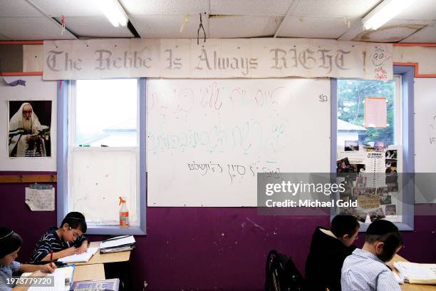 Boys studying between chalk board and banner above that reads 'The Rebbe Is Always Right" in Yeshiva Gedolah Zichron Moshe, South Fallsburg, NY, 2009.