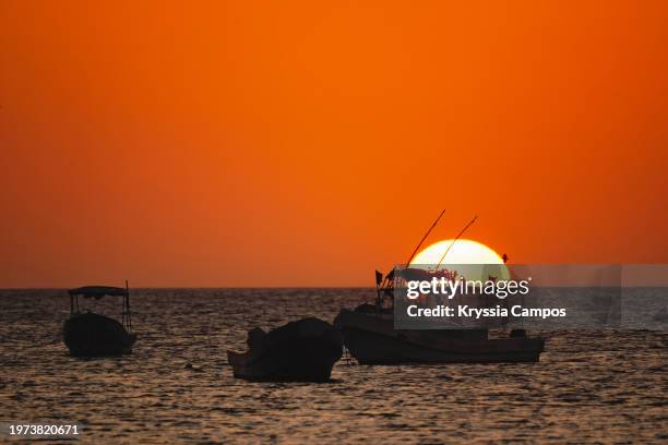 golden sunset with the sun over the sea horizon and boats in silhouettes - san juan del sur stock pictures, royalty-free photos & images