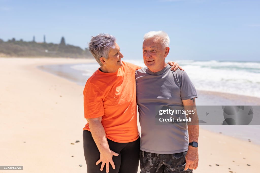 Active Senior Couple Hugging at the Beach in Summer