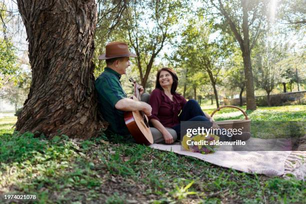 un anciano le da una serenata a su esposa con su guitarra - serenata fotografías e imágenes de stock
