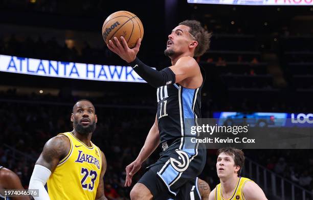 Trae Young of the Atlanta Hawks drives against LeBron James and Austin Reaves of the Los Angeles Lakers during the third quarter at State Farm Arena...