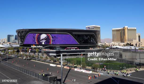 An exterior view shows an image of the Lombardi Trophy and signage for Super Bowl LVIII as workers paint numbers on the field at Allegiant Stadium on...