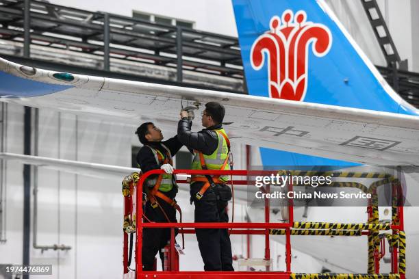 Mechanical engineers check the wings of a passenger plane at a maintenance base of China Southern Airlines to ensure the safety of flight operations...