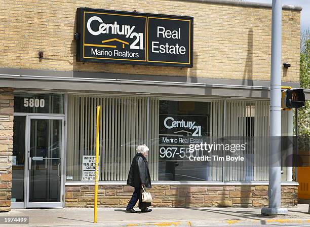 Woman walks past a Century 21 Real Estate office May 5, 2003 in Morton Grove, Illinois. Lower mortgage interest rates offset higher home prices and...