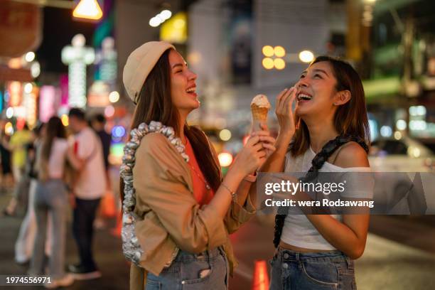 tourist women enjoying eating ice cream cone on chinatown street food festival - street food festival stock pictures, royalty-free photos & images
