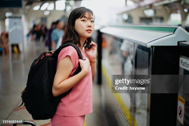 asian female traveller waiting for mrt train at station platform - singapore mrt stock pictures, royalty-free photos & images