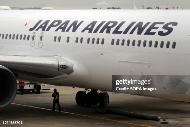 Airport worker is seen under a Japan Airlines aircraft at Tokyo Haneda International Airport Terminal 1.