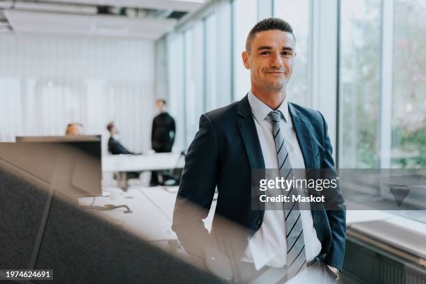 portrait of confident young businessman standing at corporate office - incidental people stock pictures, royalty-free photos & images