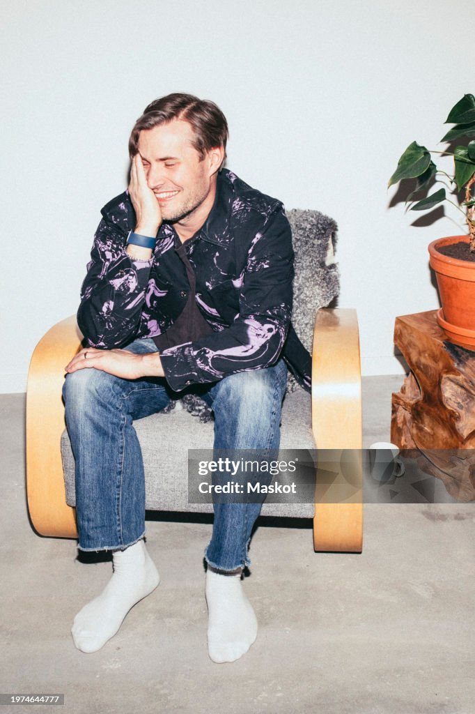 Smiling man sitting on armchair at home