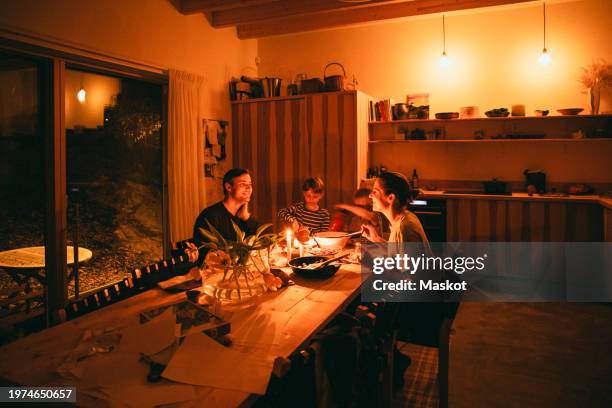 happy family enjoying candle night dinner while sitting at dining table in home - candlelight stock pictures, royalty-free photos & images