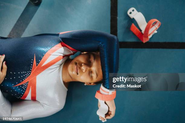 directly above shot of female teenage athlete with eyes closed resting on floor - teen female gymnast stock pictures, royalty-free photos & images