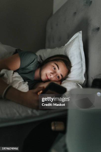 pre-adolescent girl using mobile phone while lying on bed in bedroom at smart home - pre adolescent child bildbanksfoton och bilder