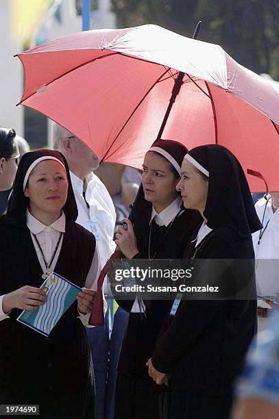 Some of the extras dressed as nuns stand under an umbrella while filming scenes of "Man On Fire" at a sports club May 5, 2003 in Mexico City, Mexico.