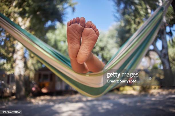unkenntliches kind, das hängematte am zelt in der natur genießt - candid feet stock-fotos und bilder