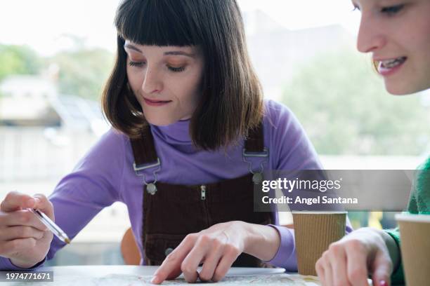 two women planning route on map at cafe - google ventures stock pictures, royalty-free photos & images