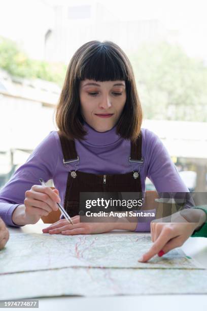 young woman focused on marking map at cafe table - google ventures stock pictures, royalty-free photos & images