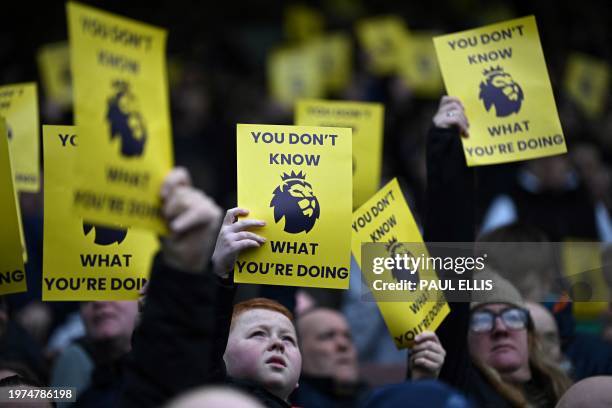 Everton supporters hold signs to protest against the English Premier League ahead of the football match between Everton and Tottenham Hotspur at...