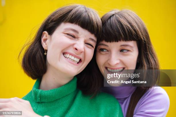 joyful sisters laughing against yellow background - tooth bonding stock pictures, royalty-free photos & images