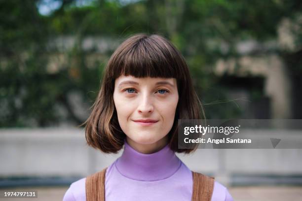 approachable young woman smiling gently in the city - annual companions stock pictures, royalty-free photos & images