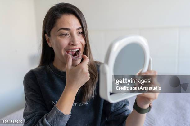 woman applying invisible teeth aligner - bruxism stock pictures, royalty-free photos & images