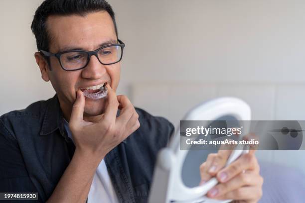 homme appliquant une gouttière de dents invisible - garder photos et images de collection