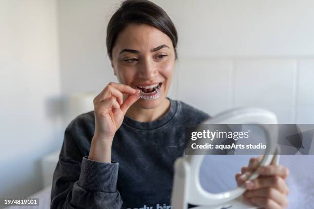 mujer aplicando alineador de dientes invisibles - guardar fotografías e imágenes de stock