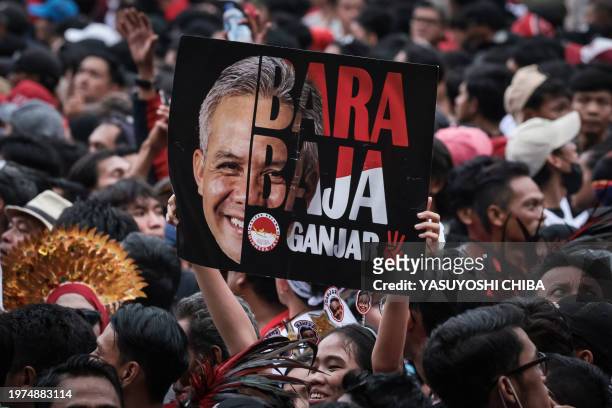 Supporter lifts a poster of presidential candidate and former Central Java governor Ganjar Pranowo during their election campaign at the Gelora Bung...